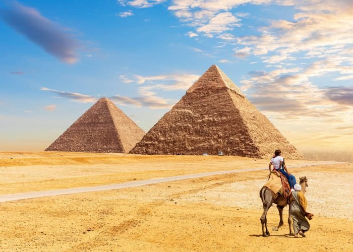Turistas Montando Un Camello Delante De Las Piramides De Giza